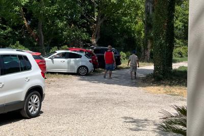 Maison avec terrasse entourée de végétation, située dans un jardin avec allée en gravier et ciel dégagé en arrière-plan.