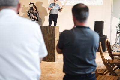 Miniature Location salle Meyrargues (Bouches-du-Rhône) - Château de Vauclaire #4 Groupe de personnes assises et discutant dans un jardin ensoleillé avec des parasols blancs.