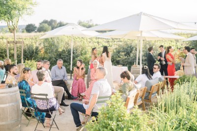Miniature Location salle Meyrargues (Bouches-du-Rhône) - Château de Vauclaire #12 Groupe de personnes assises et discutant dans un jardin ensoleillé avec des parasols blancs.