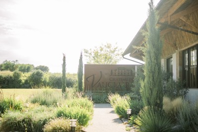 Miniature Location salle Meyrargues (Bouches-du-Rhône) - Château de Vauclaire #3 Groupe de personnes assises et discutant dans un jardin ensoleillé avec des parasols blancs.