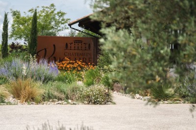 Miniature Location salle Meyrargues (Bouches-du-Rhône) - Château de Vauclaire #2 Groupe de personnes assises et discutant dans un jardin ensoleillé avec des parasols blancs.