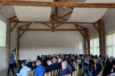 Miniature Amphithéâtre Groupe de personnes assises et discutant dans un jardin ensoleillé avec des parasols blancs.
