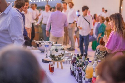 Miniature Cocktail sur la terrasse bordée de vignes Groupe de personnes assises et discutant dans un jardin ensoleillé avec des parasols blancs.