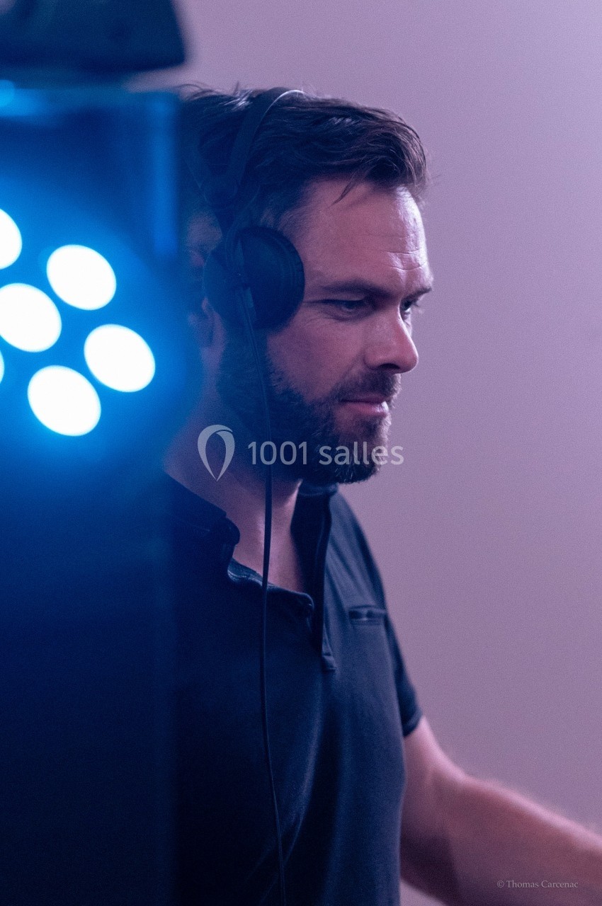 Un homme portant un casque audio mixe de la musique dans une ambiance lumineuse tamisée.