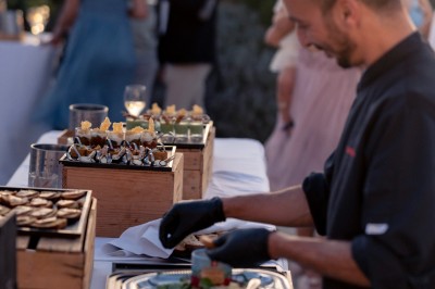 Miniature Nos traiteurs partenaires à votre service Groupe de personnes assises et discutant dans un jardin ensoleillé avec des parasols blancs.
