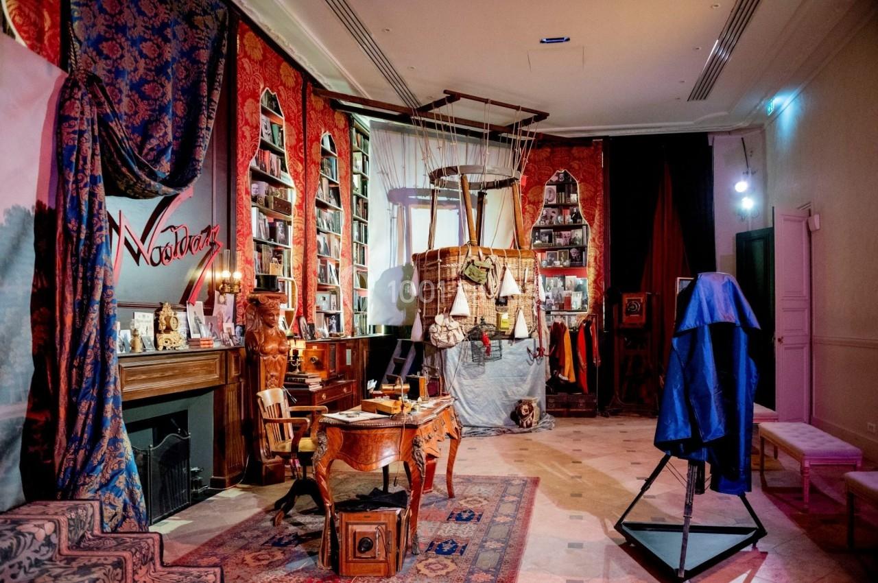 Salle décorée avec des meubles anciens, des étagères remplies de livres et un décor évoquant un voyage en montgolfière.