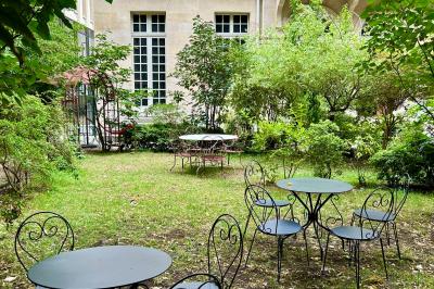 Salle lumineuse avec parquet, tapis décoré, fresques murales, rideaux sombres et plafond orné d'une carte céleste.