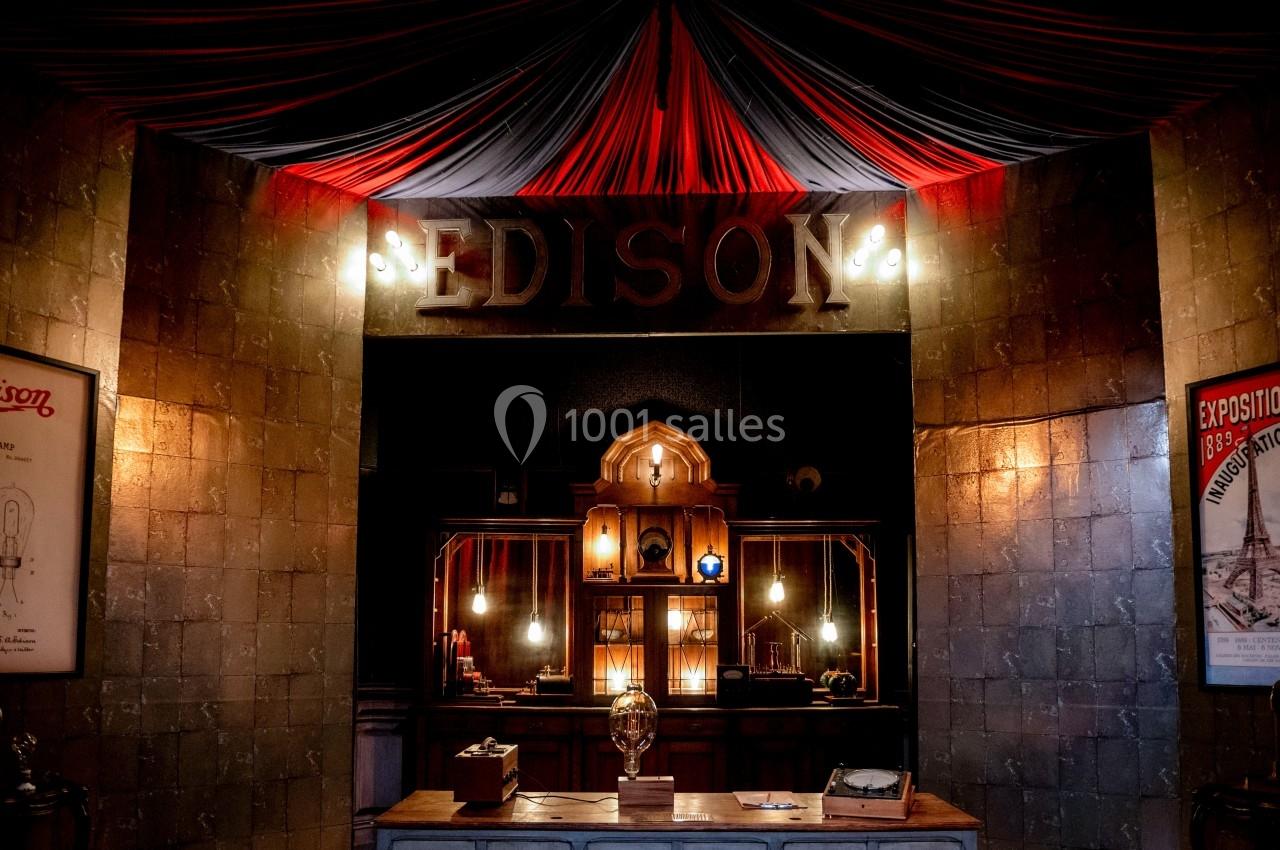 Entrée d'un espace décoré avec des lumières vintage, une enseigne ’Edison’ et des affiches rétro sur les murs.