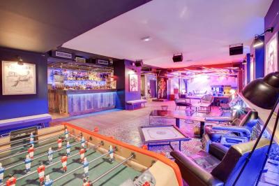 Escalier intérieur avec rampe rouge, éclairé par des néons roses et décoré de motifs lumineux sur les murs sombres.