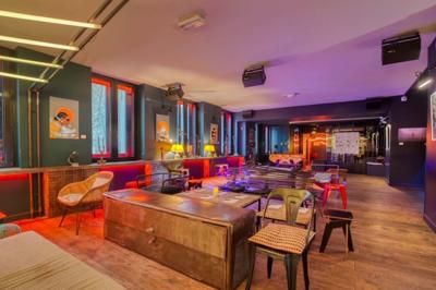 Escalier intérieur avec rampe rouge, éclairé par des néons roses et décoré de motifs lumineux sur les murs sombres.
