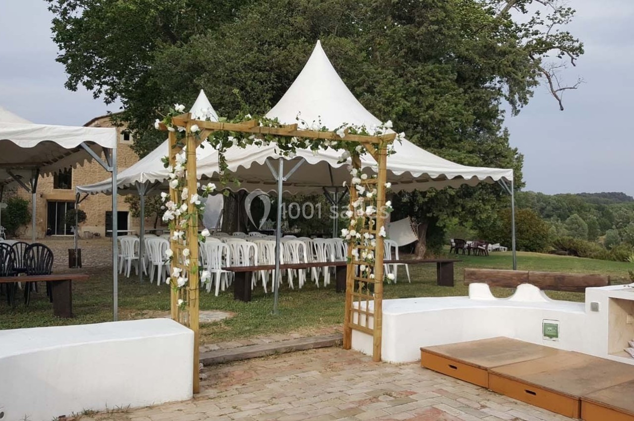 Tentes blanches et arche fleurie installées dans un jardin pour un événement en plein air.