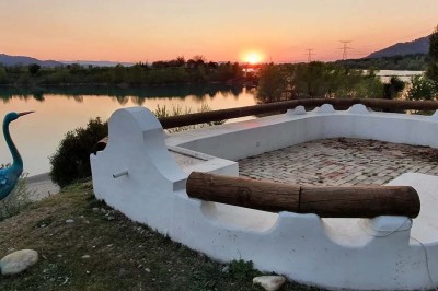 Chambre avec lit double bleu, tête de lit en rotin, décoration sobre et tableau représentant un ponton sur la mer.