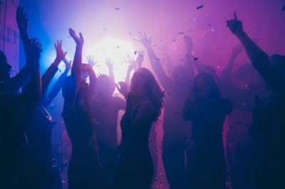 Un couple s'embrasse sous une arche, entouré d'invités tenant des cierges magiques allumés dans l'obscurité.