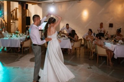 Un couple s'embrasse sous une arche, entouré d'invités tenant des cierges magiques allumés dans l'obscurité.