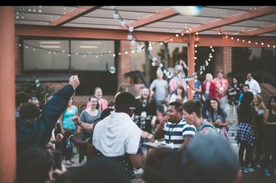 Un couple s'embrasse sous une arche, entouré d'invités tenant des cierges magiques allumés dans l'obscurité.