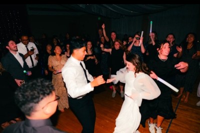 Un couple s'embrasse sous une arche, entouré d'invités tenant des cierges magiques allumés dans l'obscurité.