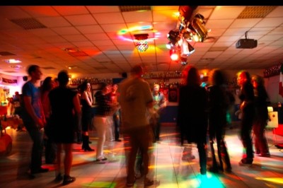 Un couple s'embrasse sous une arche, entouré d'invités tenant des cierges magiques allumés dans l'obscurité.