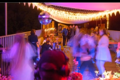 Un couple s'embrasse sous une arche, entouré d'invités tenant des cierges magiques allumés dans l'obscurité.