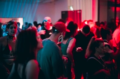 Groupe de personnes dans une salle sombre éclairée par des lumières rouges, ambiance festive et animée.