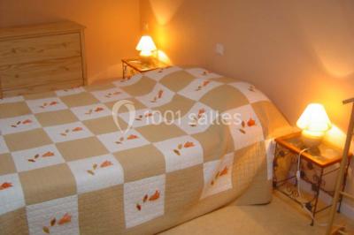 Chambre avec un lit double, une lampe de chevet allumée, un lit superposé en bois et un mur peint en rose pâle.