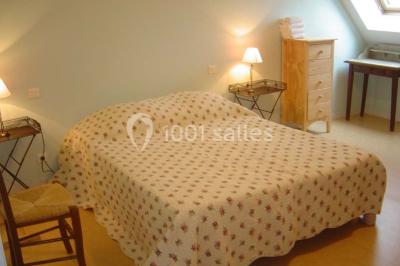 Chambre avec un lit double, une lampe de chevet allumée, un lit superposé en bois et un mur peint en rose pâle.