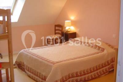 Chambre avec un lit double, une lampe de chevet allumée, un lit superposé en bois et un mur peint en rose pâle.