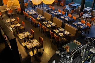 Miniature Location salle Ronchin (Nord) - Leocorno #3 Vue d'un restaurant moderne avec de grandes baies vitrées, des tables dressées et des luminaires suspendus en osier.