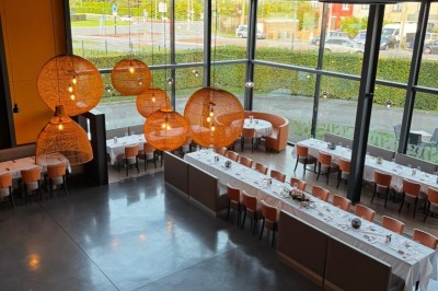 Miniature Location salle Ronchin (Nord) - Leocorno #5 Vue d'un restaurant moderne avec de grandes baies vitrées, des tables dressées et des luminaires suspendus en osier.