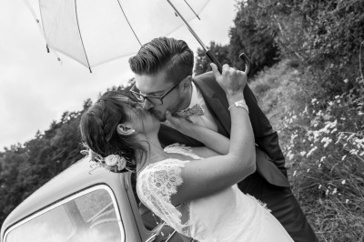 Miniature Anthony Delassise Photographe #2 Silhouettes d'un couple s'embrassant sous une arche ornée de feuillage, en contre-jour.