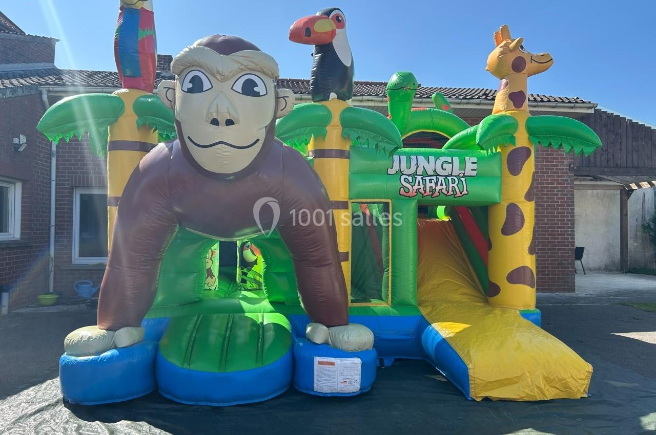 Structure gonflable colorée sur le thème de la jungle avec un singe, un toucan, un perroquet et une girafe.
