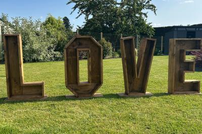 Trois valises vintage empilées, en cuir et tissu, posées sur une surface en extérieur avec de l'herbe en arrière-plan.