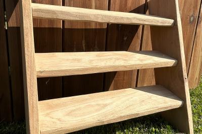 Trois valises vintage empilées, en cuir et tissu, posées sur une surface en extérieur avec de l'herbe en arrière-plan.