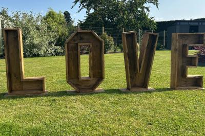 Trois valises vintage empilées, en cuir et tissu, posées sur une surface en extérieur avec de l'herbe en arrière-plan.