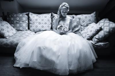 Un couple en tenue de mariage s'embrasse dans un champ de blé, tenant des ballons colorés sous un ciel bleu.