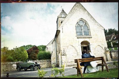 Un couple en tenue de mariage s'embrasse dans un champ de blé, tenant des ballons colorés sous un ciel bleu.
