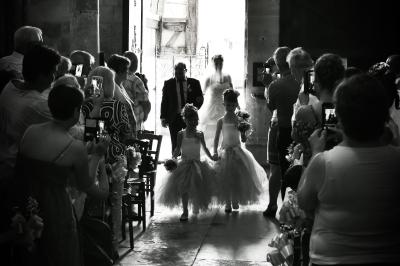Un couple en tenue de mariage s'embrasse dans un champ de blé, tenant des ballons colorés sous un ciel bleu.