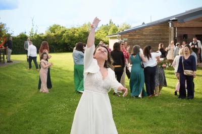 Un couple en tenue de mariage danse dans un jardin baigné par une lumière dorée.