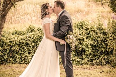Un couple en tenue de mariage danse dans un jardin baigné par une lumière dorée.