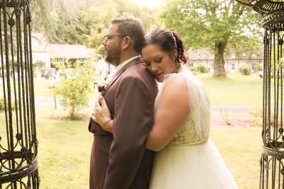 Un couple en tenue de mariage danse dans un jardin baigné par une lumière dorée.