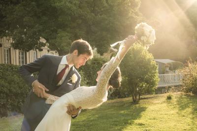 Un couple en tenue de mariage danse dans un jardin baigné par une lumière dorée.