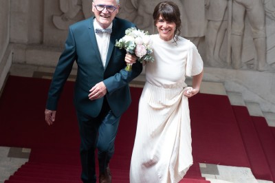 Voiture ancienne décapotable décorée de fleurs pour une cérémonie, stationnée sur une rue pavée.