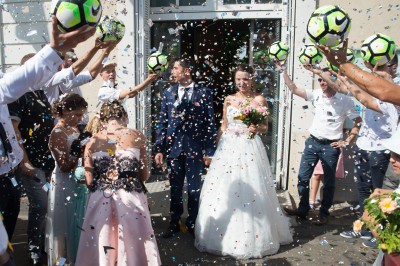 Voiture ancienne décapotable décorée de fleurs pour une cérémonie, stationnée sur une rue pavée.