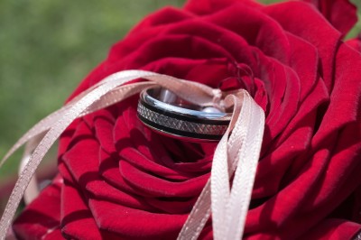 Voiture ancienne décapotable décorée de fleurs pour une cérémonie, stationnée sur une rue pavée.