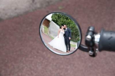 Voiture ancienne décapotable décorée de fleurs pour une cérémonie, stationnée sur une rue pavée.