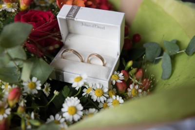Voiture ancienne décapotable décorée de fleurs pour une cérémonie, stationnée sur une rue pavée.