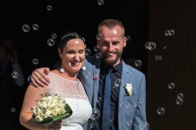 Voiture ancienne décapotable décorée de fleurs pour une cérémonie, stationnée sur une rue pavée.
