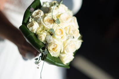 Voiture ancienne décapotable décorée de fleurs pour une cérémonie, stationnée sur une rue pavée.