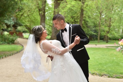 Voiture ancienne décapotable décorée de fleurs pour une cérémonie, stationnée sur une rue pavée.