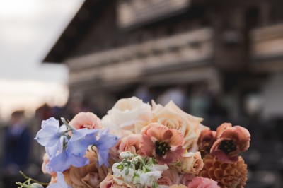 Miniature Location salle La Clusaz (Haute-Savoie) - Le 1647 #9 Un couple en tenue de mariage se tient dans un paysage montagneux au coucher du soleil, entouré de sapins.