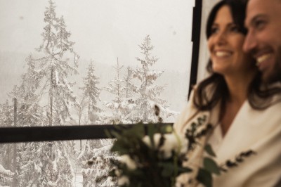Miniature Location salle La Clusaz (Haute-Savoie) - Le 1647 #10 Un couple en tenue de mariage se tient dans un paysage montagneux au coucher du soleil, entouré de sapins.